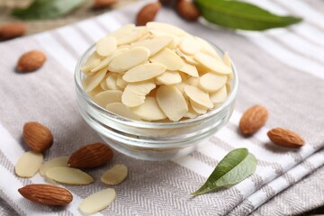 Fresh almond flakes and whole nuts on table, closeup