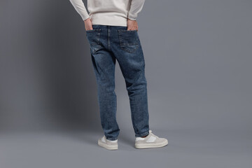 Naklejka premium Man in stylish jeans on grey background, closeup