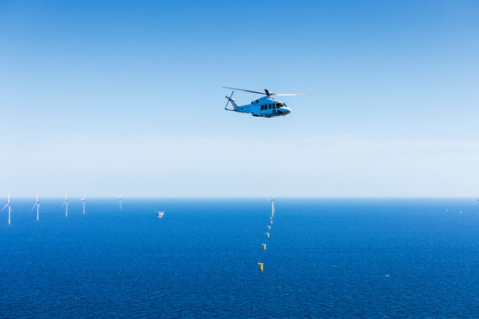 Helicoptor flying over a wind farm in the Baltic Sea returning from a crew change at an installation vessel..