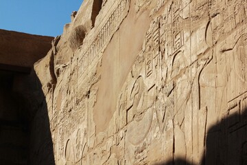 Ancient Egyptian stone wall with carved hieroglyphs and image of snake and a pharaoh