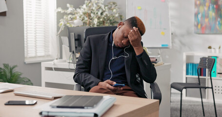 A multi-racial man in a suit, sitting at his desk in the office, is bored and tired with no work. He swivels in his chair, listens to music, watches movies on his phone, and writes messages.
