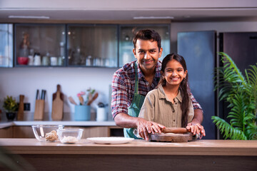 Fototapeta premium indian Father teaching daughter chapati making in modern kitchen, family quality time