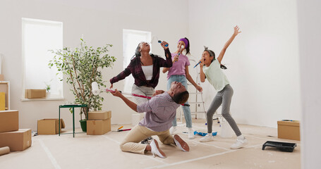 During their apartment renovation, a happy family dances and sings in the room. The mother and daughters treat the rollers as microphones, while the father pretends to play music with a brush.