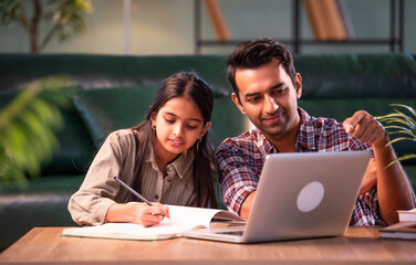 Fototapeta premium Indian Father helping daughter study on laptop, family learning and bonding at home