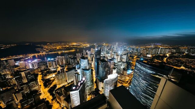 High-angle aerial shot of a contemporary city glowing under deep blue sky, neon signs and glass facades emphasizing modern development, with copy space