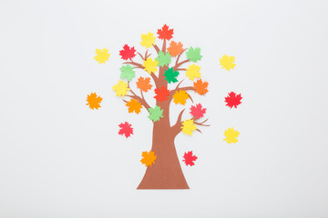 Created brown tree with colorful maple leaves from application paper on light gray table background. Closeup. Making autumn decoration. Child handcraft. Top down view.
