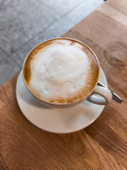 Coffee cup with frothy milk on wooden table, showcasing warm autumn ambiance and cozy atmosphere