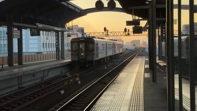 At Kochi Station in Japan at Dawn: A Retro Train Slowly Departs from the Platform, with Railway Facilities and the Orange Sky Weaving a Poetic Commute Scene.