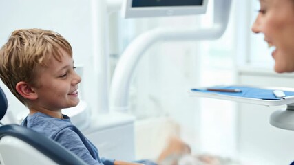 Smiling boy giving a high five to a female dentist after a successful dental check up.