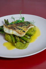 Braised perch fillet served with green asparagus and creamy spinach purée, a healthy and elegant seafood dish perfect for gourmet cuisine.