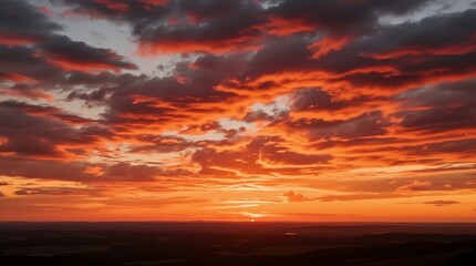 Obraz premium Vibrant sunset hues painting the sky, with fiery clouds and a serene horizon.