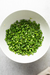 Overhead view of diced green beans, top view of green beans, sliced haricot verts on a white countertop, process of making nigerian fried rice
