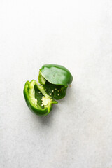 Overhead view of green bell peppers being sliced on a marble countertop, top view of green bell peppers