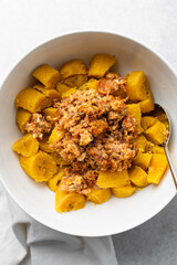 overhead view of Boiled ripe plantain with tomato scrambled eggs in a white bowl, top view of nigerian egg and plantain