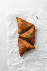 Overhead view of samosa on parchment paper, top view of beef samosa on a white background