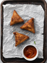 Overhead view of samosa on parchment paper, top view of beef samosa on a white background