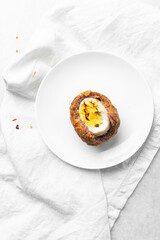 Overhead view of fried scotch eggs on white plate, top view of cross-section of scotch eggs on white dish