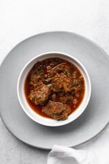 Overhead view of miyan taushe in a white bowl, top view of northern nigerian miyan taushe soup on a white countertop	