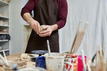 Young man skillfully crafting pottery in a bright and creative studio environment