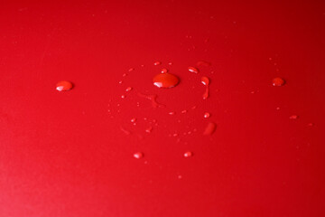 The minimalist composition water drops scattered on a red surface with soft lighting and shallow depth of field. Perfect for abstract backgrounds, clean design, or advertising to hydration and purity