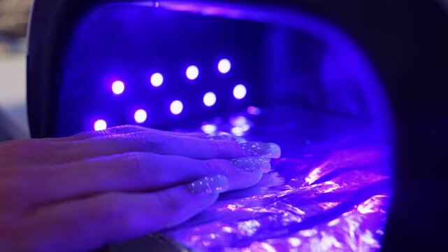 The ultraviolet lamp turns on when the client raises her hand. Drying the gel on the nails. High quality 4k footage