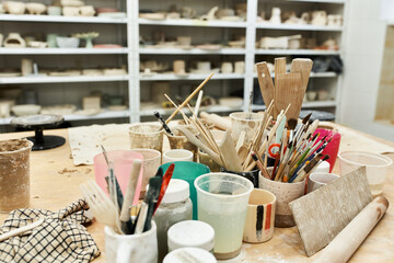 Creative chaos unfolds in a well lit pottery studio filled with colorful tools and materials
