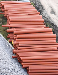 Stacked industrial orange pipes in outdoor construction site setting