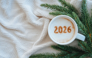 Coffee mug with milk foam and the numbers 2026 visible, set against a festive New Year's background.