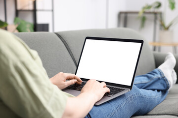 Woman working with laptop on sofa indoors, closeup. Mockup for design