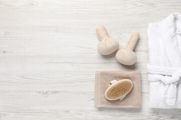 Flat lay composition with bathrobe and spa supplies on white wooden background. Space for text