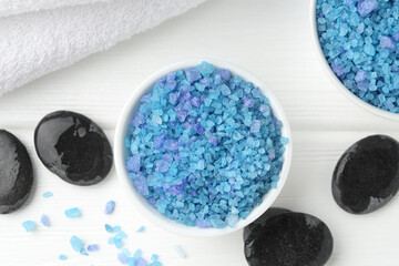 Blue sea salt, spa stones and towel on white wooden table, flat lay