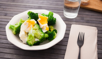 boiled broccoli inflorescences with boiled egg in plate