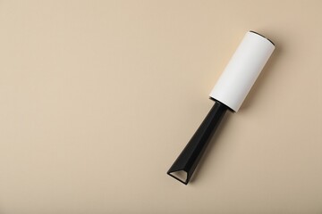 One lint roller on beige background, top view. Space for text