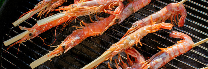 Grilled prawns on skewers sizzle, evoking coastal Tango no Sekku festivities and rustic...