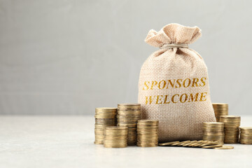 Bag with phrase Sponsors Welcome and coins on white table
