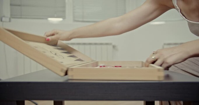 A woman's hands meticulously prepare a backgammon board, arranging the checkers and rolling the dice. The video captures the crisp, satisfying sounds of the game pieces.
