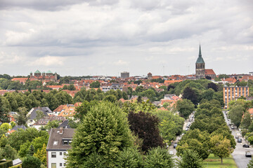 Obraz premium Panoramic view of Hildesheim city in Lower Saxony, Germany, with historic churches, red rooftops, and green trees under cloudy sky