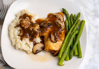 chicken breast top with gravy and mushrooms