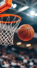 Fototapeta premium A basketball is about to go through the hoop in a basketball game with a crowd watching below