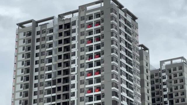 High-rise construction site with cranes and Vietnam flags waving in the wind