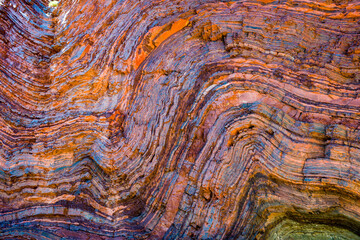 Vividly coloured and contorted rock strata in ancient layered gorge walls