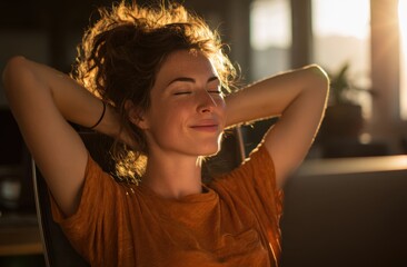 Relaxed woman with curly hair smiling with eyes closed and hands behind head