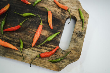 An artistic arrangement of colorful chili peppers on a distressed wooden cutting board, offering...