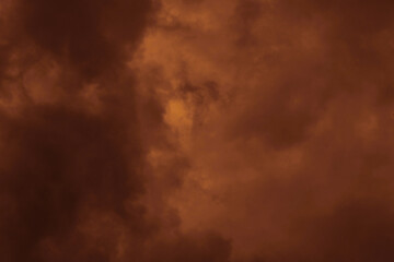 Dark brown and orange sunset stormy sky with fluffy clouds. Dramatic moody sky. Halloween cloudscape background concept.