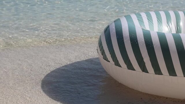 Inflatable swim ring bobbing on sunlit beach waves. Summer fun, safety, and seaside relaxation. Backdrop for travel, vacation, and leisure lifestyle themes