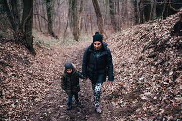 Mother and son hiking forest trail holding hands