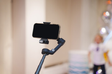 Smartphone on a gimbal stabilizer capturing a moment at a lively event indoors
