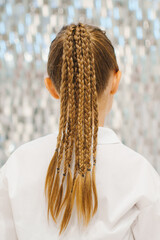 Girl with trendy braids poses by a sparkling backdrop