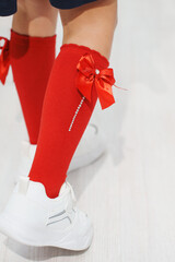 Fashionable red socks with bows and rhinestones worn by a child indoors