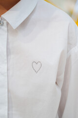 Simple white shirt featuring a delicate heart design on the chest